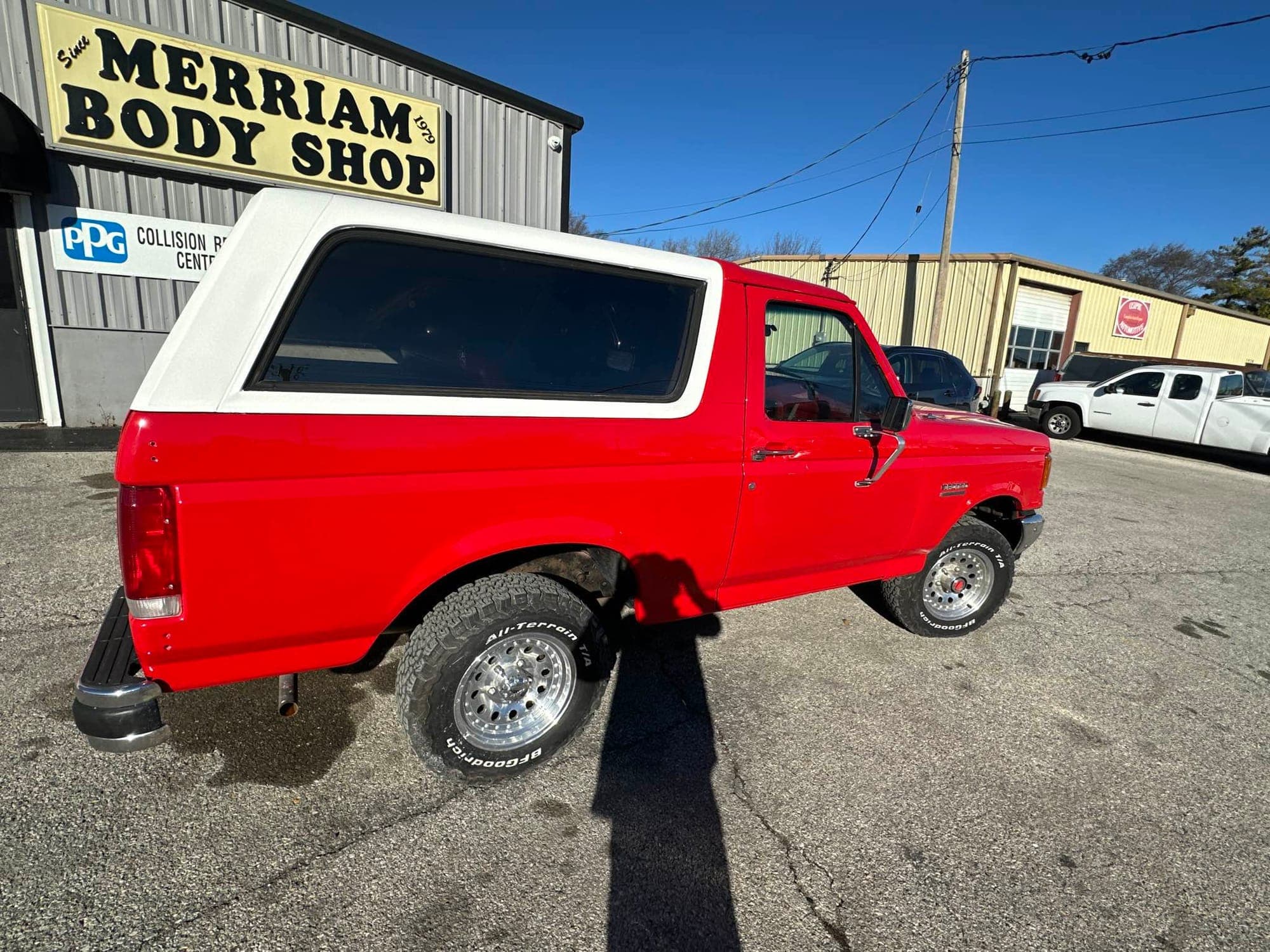 The finished red and white Bronco in front of the Merriam Body Shop sign